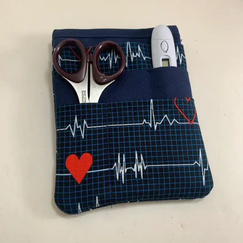Cloth nurse pocket organizer with scissors and thermometer in it. 