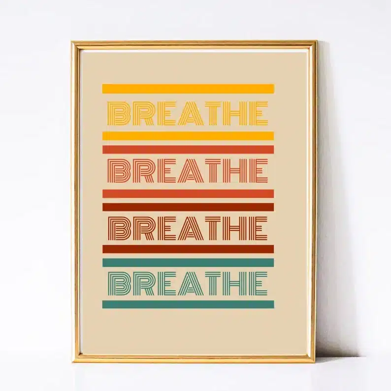 Gold framed artwork that says Breathe four times all different colored retro font, yellow, orange, red, and blue. 