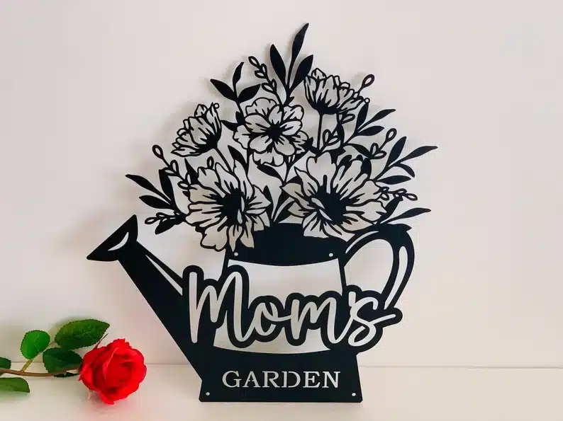 Black steel cutout garden sig that is a watering can with flowers sticking out and MOM's garden on it. 