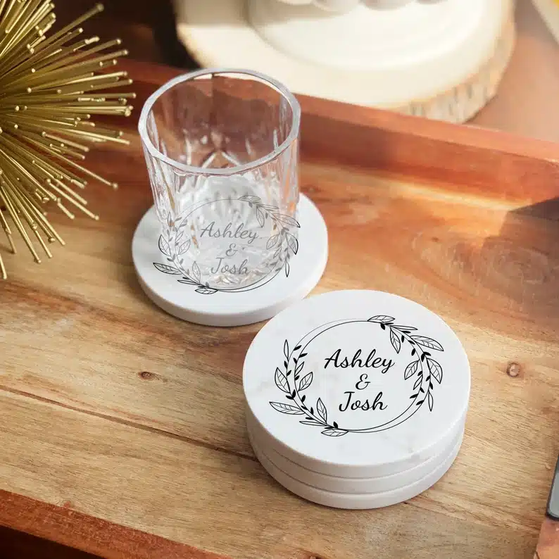 White round coasters with the names Ashley and Josh in black ink on them. 