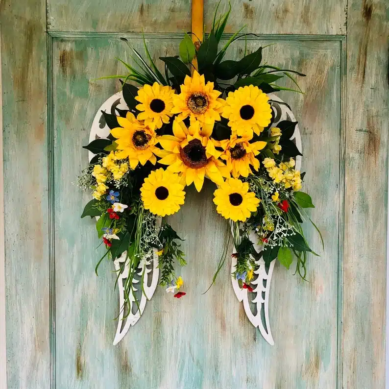 Angel wings shaped flower wreath full of sunflowers and greenery. 