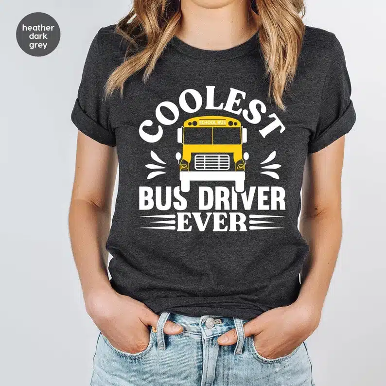 Great Gift Ideas For School Bus Drivers: CLose up of woman wearing a dark grey t-shirt with white font that says coolest bus driver ever" and a school bus on it. 