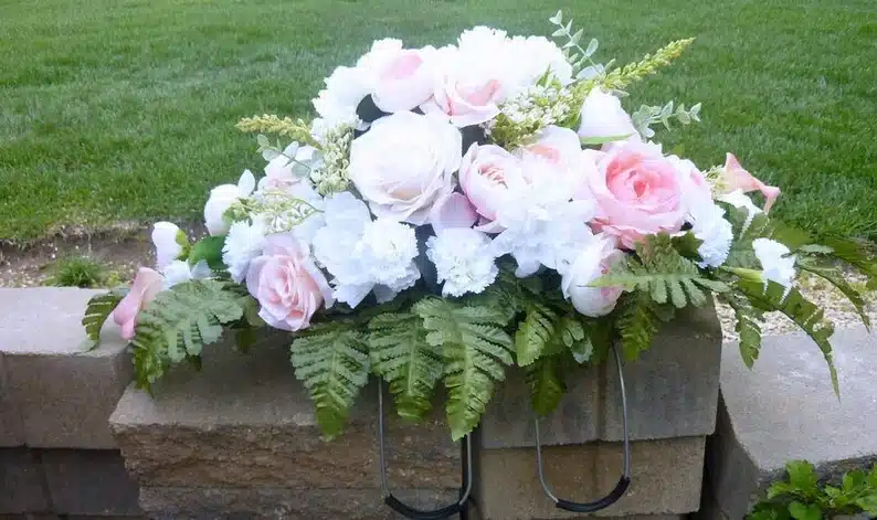 Gravestone with pink roses and white peony's on top. 