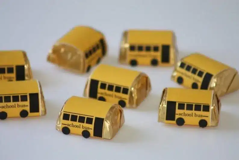 Eight small Hersey chocolate candies all wrapped in yellow paper that looks like school buses. 