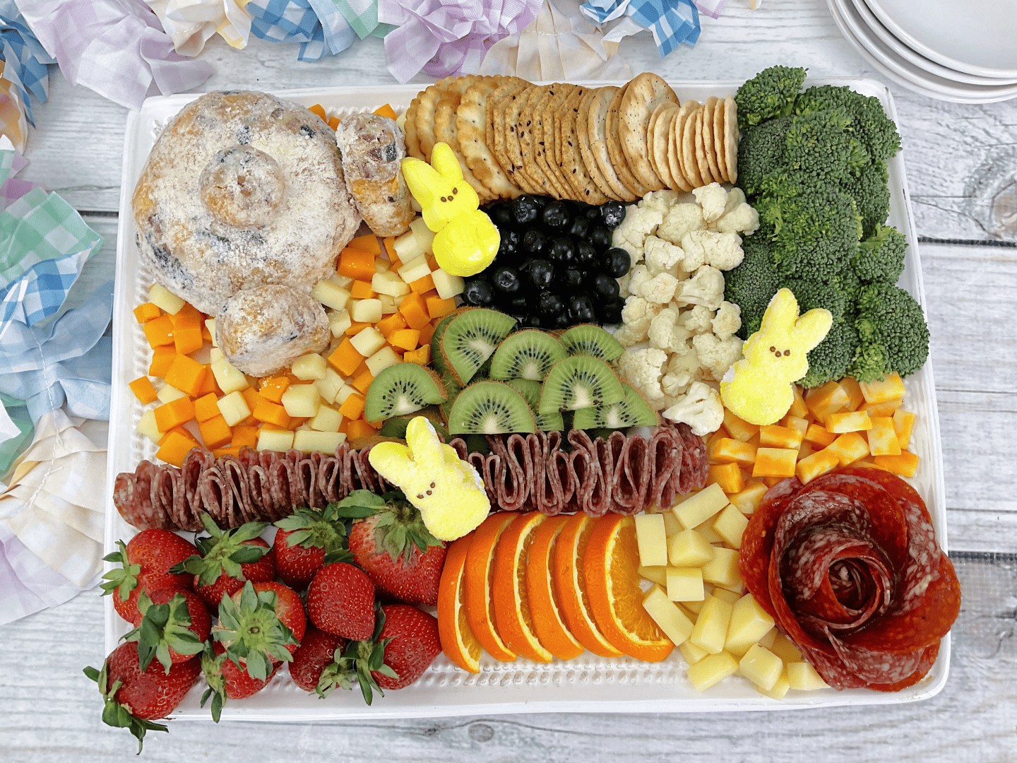 Bunny Butt Cheeseball  & Charcuterie Board: bunny cheese ball, 4 types of crackers, 4 types of cheese, various meats, oranges, strawberries, marshmallow peeps, kiwi, blueberries, cauliflower, broccoli, and pineapple. 
