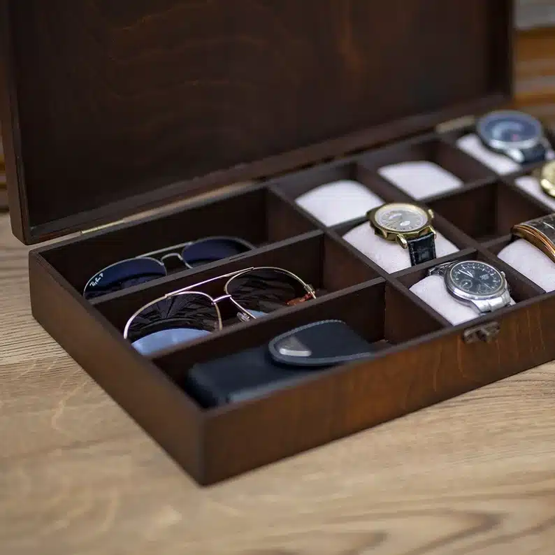 Dark wood box with black valet inside, spaces to hold sunglasses and watches. 
