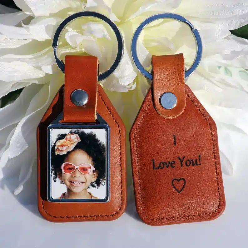 Light brown keychain ring, one with a photo of a giel on one side and the other it says I love you!
