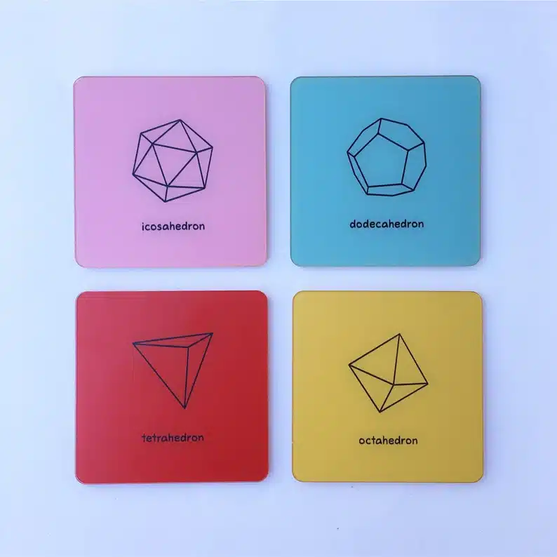 Four math coasters, light pink, light blue, red, and yellow with different 4D shapes on them. 