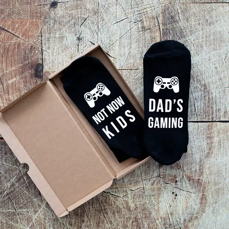 Bow with black socks on it, white font that says Not now kids one one and Dad's gaming on the other. Both with a controller on them. 