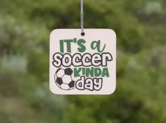 Car air freshener - white square that says it's a soccer kinda day. 