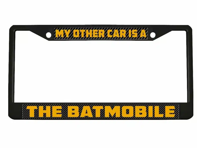 Black license plate with yellow font that says "my other car is a The Batmobile."