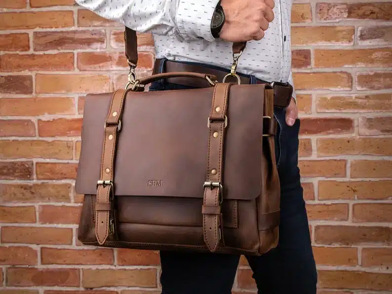 Close up of man holding a brown leather laptop bag. 