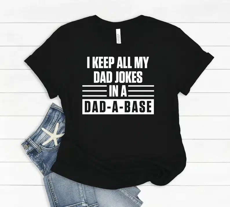 Black t-shirt with white font that says I keep all my dad jokes in a dad-a-base. 