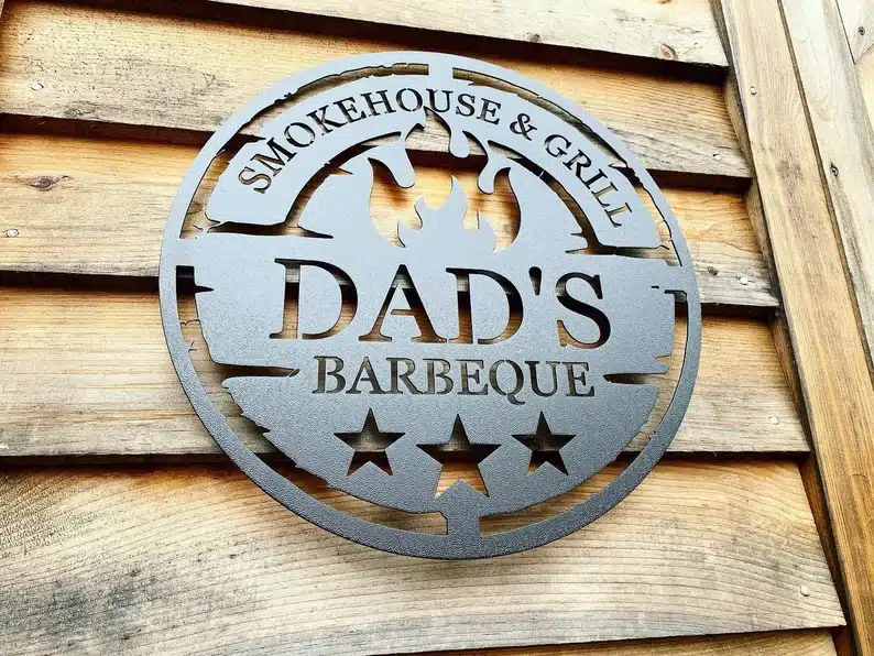 Metal sign that says Smokehouse & grill Dad's barbeque. 