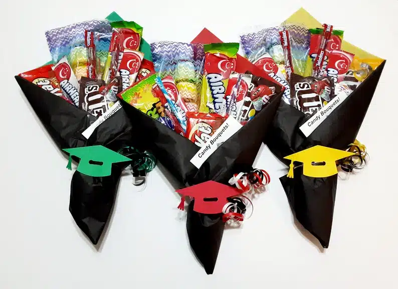 Kindergarten Graduation Candy Bouquets - three all black wrapped with a different grad cap color on it, green, red, and yellow. all filled with various candies. 