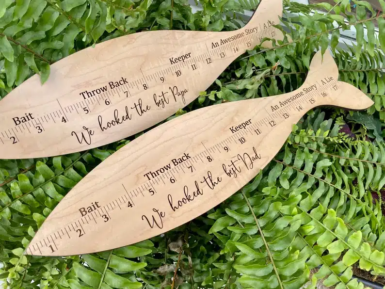 Two wooden shaped fishes that are also rulers. 