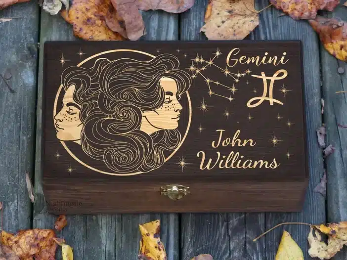 Wooden box with Gemini symbol and constellation symbols in gold on top. 