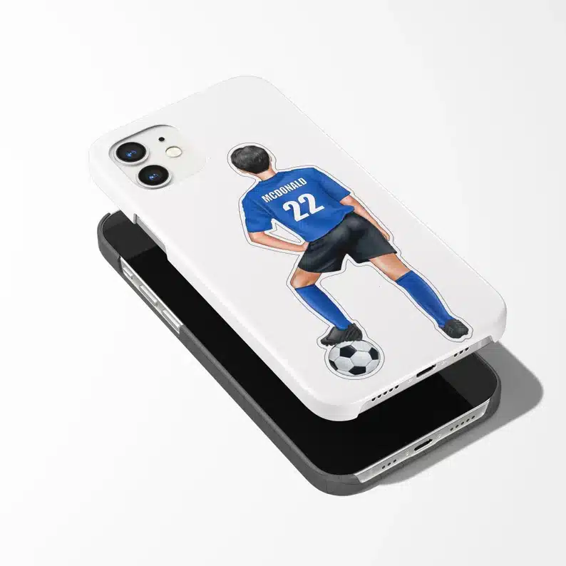 White cellphone with a sticker of a boy wearing a blue soccer shirt with one foot on a soccer ball. 