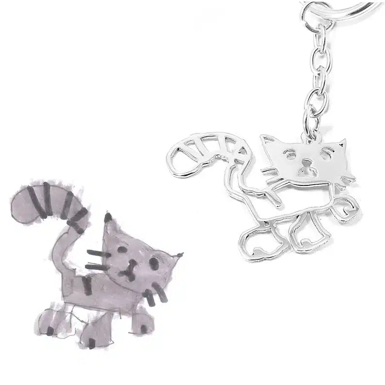 Kids drawing keychain, drawing of a grey and black cat made into a silver keychain. 