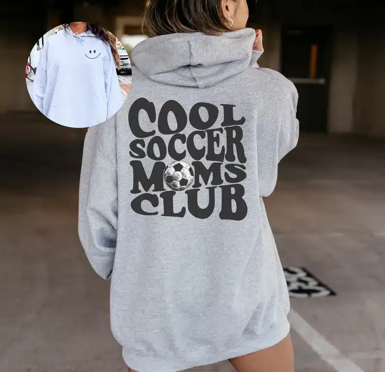 Back of a light grey hoodie with large black font that says Cool soccer moms club. 