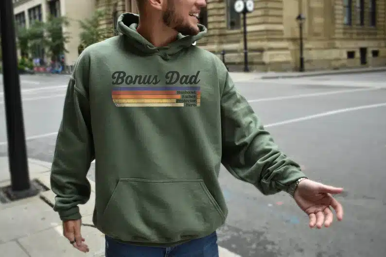 Man wearing a green hoodie that says Bonus dad. 