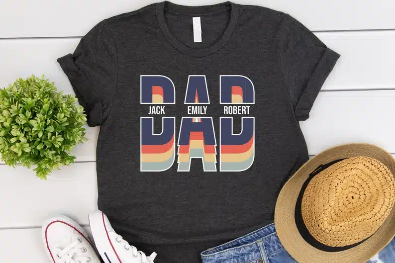 Black t-shirt that says DAD on it with three kids names on it. 