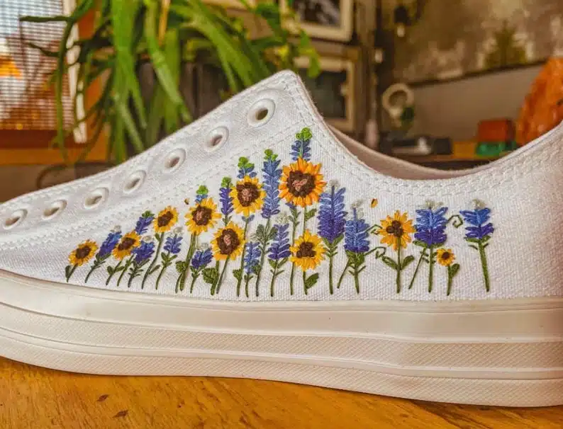 White shoe with embroidered sunflowers and purple flowers on it. 