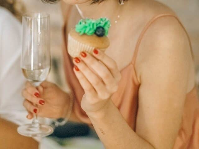 Woman holding a cupcake and glass of wine