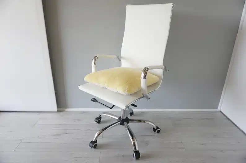 White chair with a white fluffy pillow on it. 