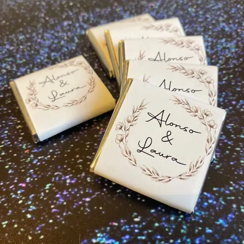 Six white square wrapped chocolates with custom names on it. 