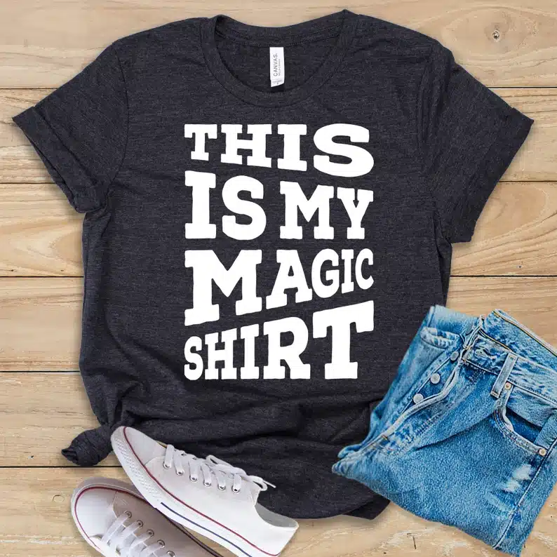 Black t-shirt with white font that says "this is my magic shirt" 