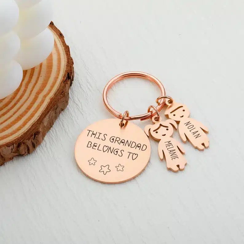 Rose gold keychain with round tag that says This grandad belongs to and two little kid keychains that says Melanie and Nolan 