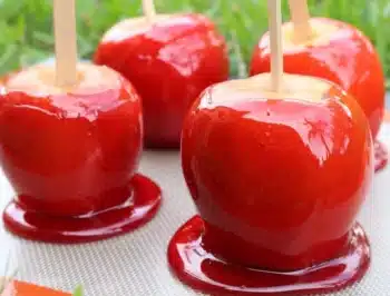 four apples on a stick covered in red candy. 