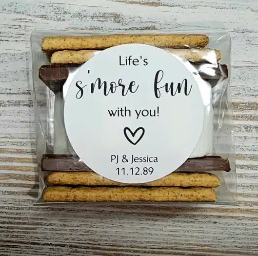 The Most Delicious Edible Wedding Favors - Small package with graham crackers, chocolate, and marshmallows with a customizable white round sticker on it. 