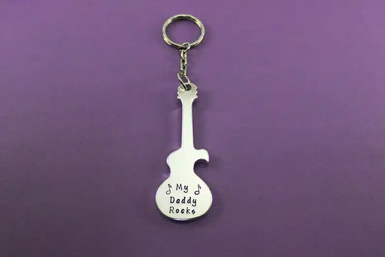 Silver guitar shaped bottle opener keychain that says My Daddy rocks. 