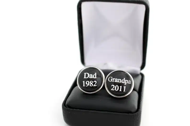 Black round cufflinks that say Dad 1982 on one and Grandpa 2011 on the other in white. 