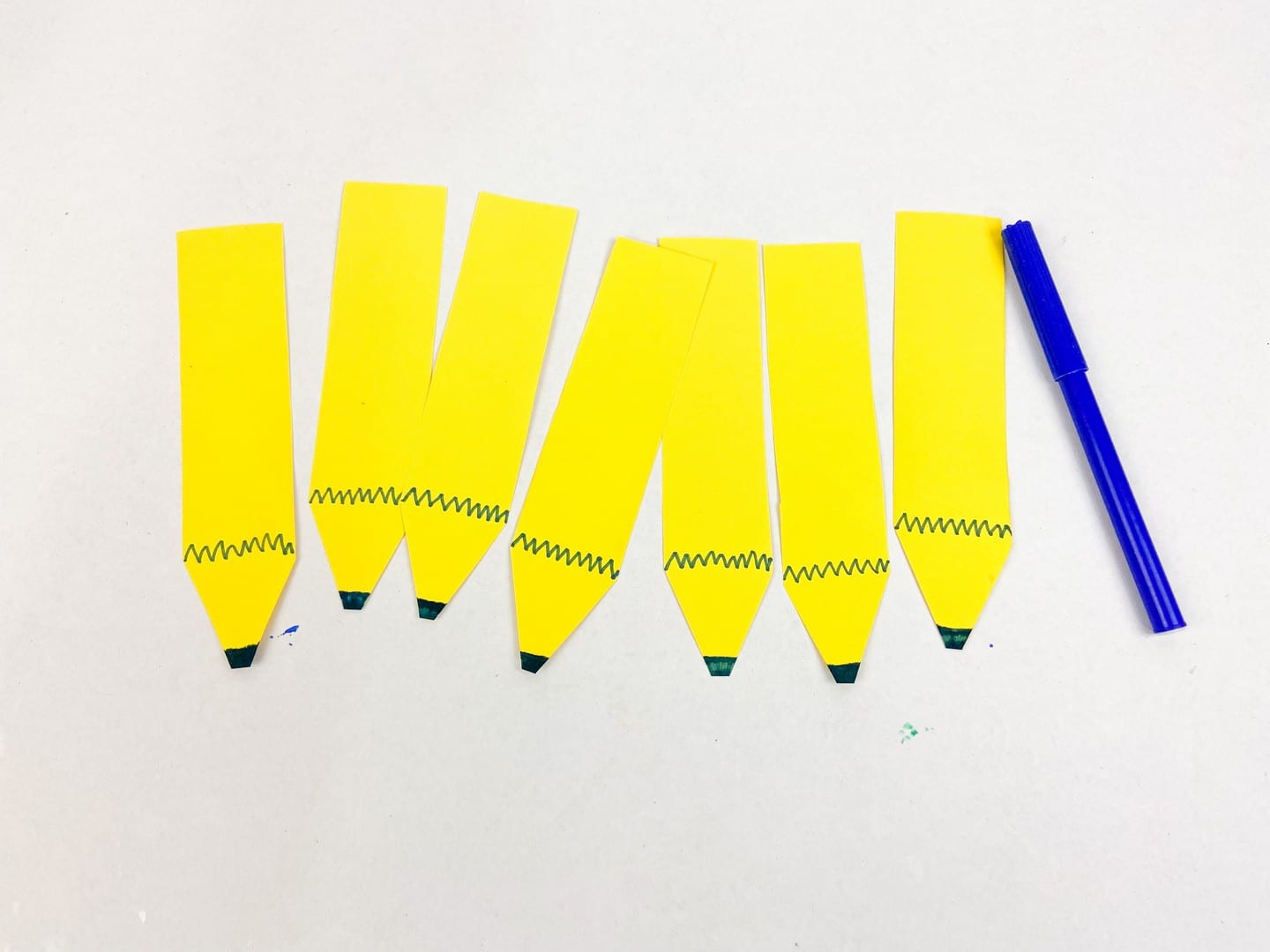 Yellow pencils with a blue marker beside them with blue zig zags on them and blue ends. 