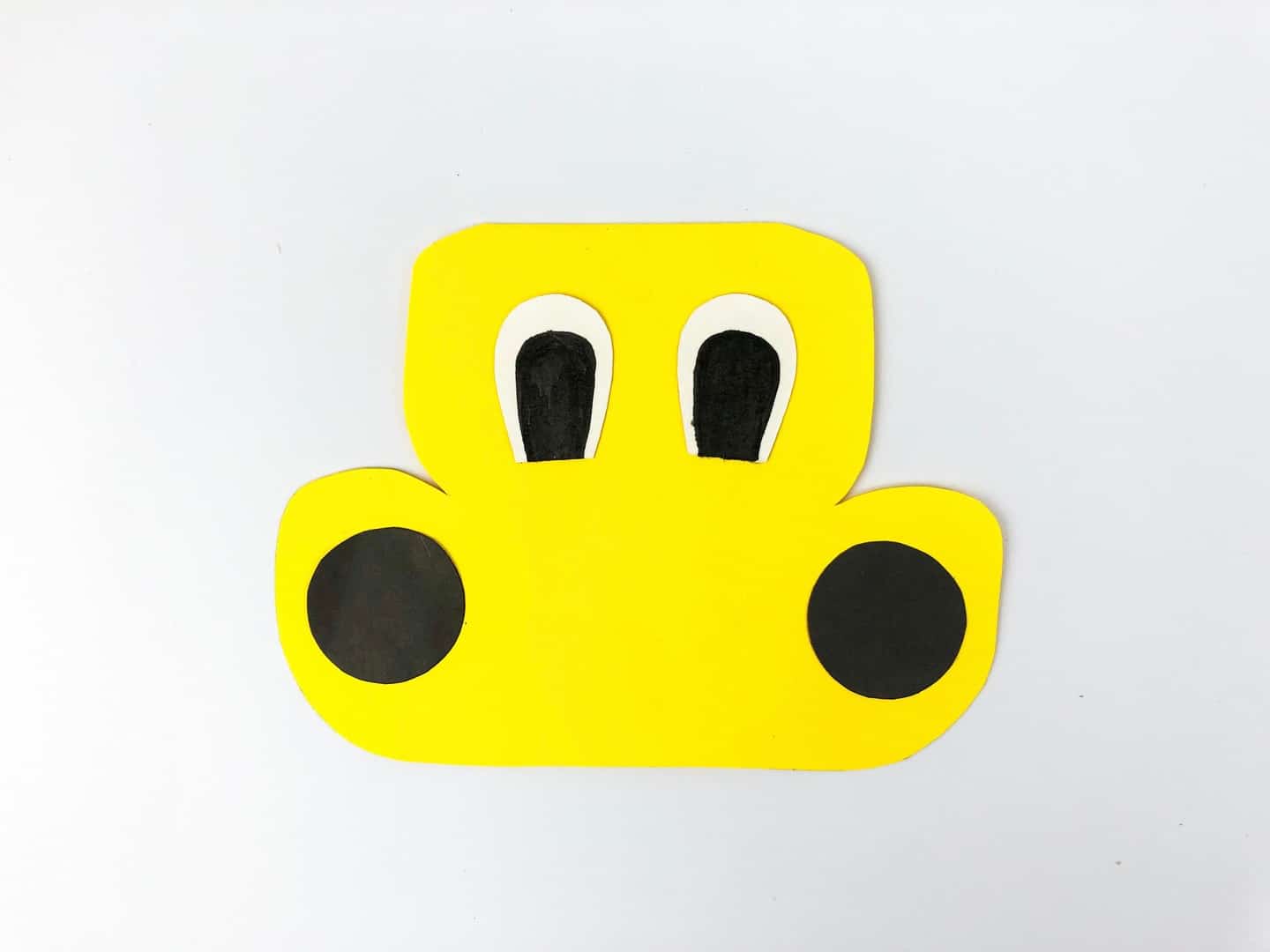 Yellow school bus card with eyes and now black circle headlights glued on. 