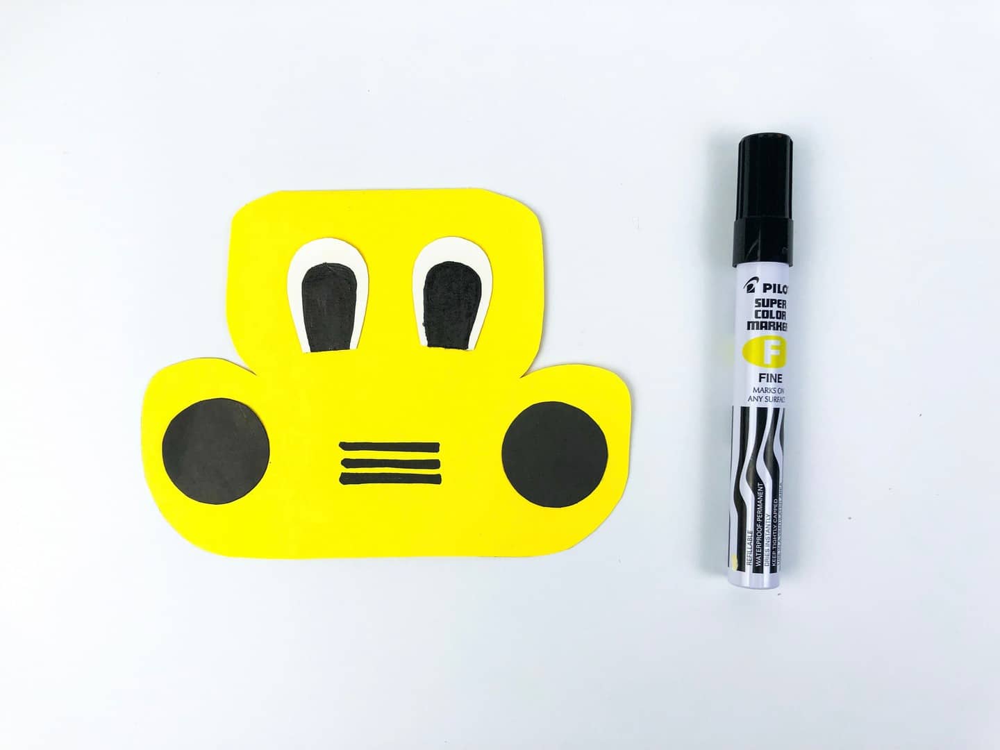 Yellow school bus with eyes, headlights, and three black grill lines drawn on. 