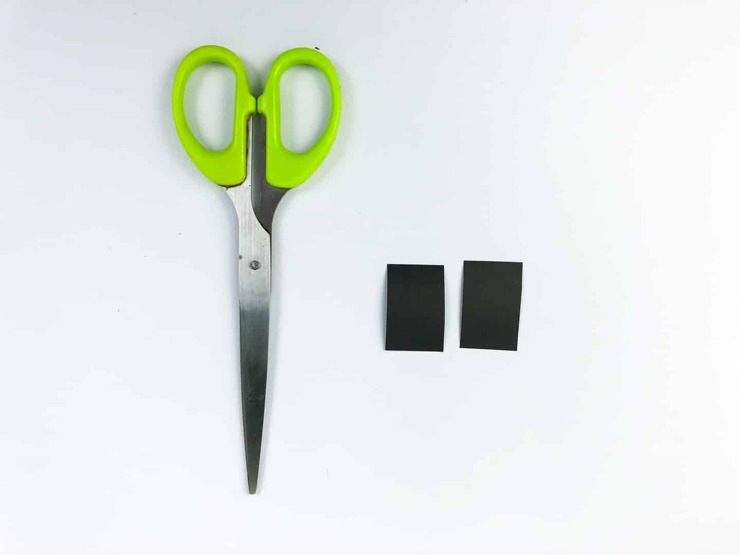 Scissors with two rectangle black tires cut out beside them. 