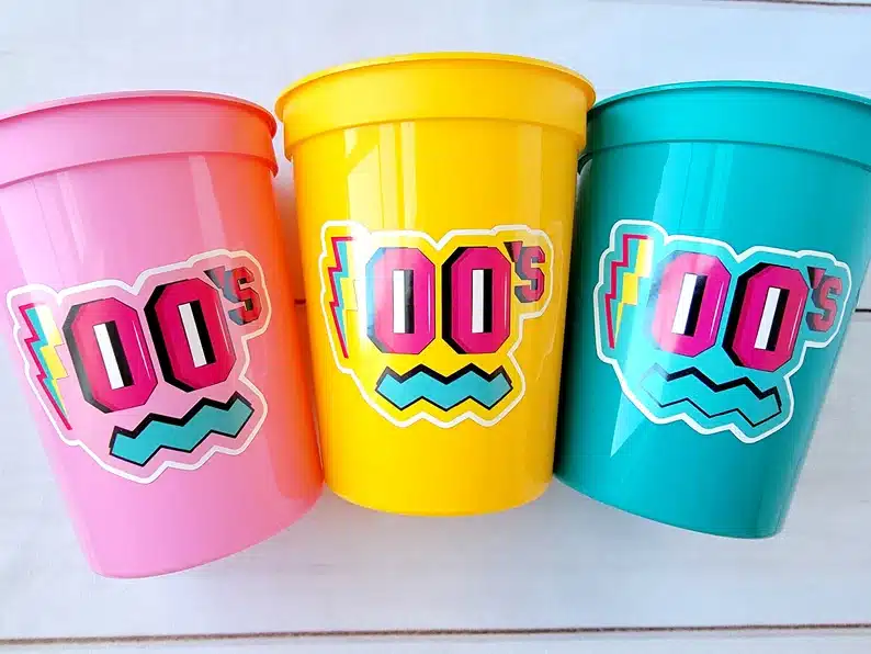 Three brightly colored party cups that says 00's on it. 