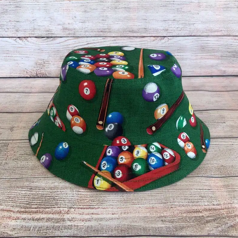 Green bucket hat with pool balls and sticks all over it. 