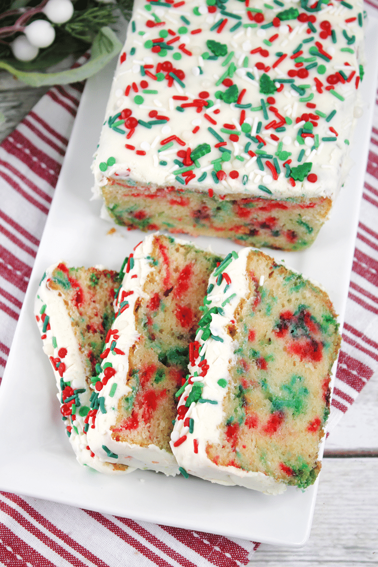 Cake with white glaze on top with red, white, and green festive shaped and colored sprinkles.