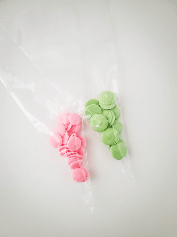 Two ziplock bags one wiht pink candy melts and the other with green candy melts.