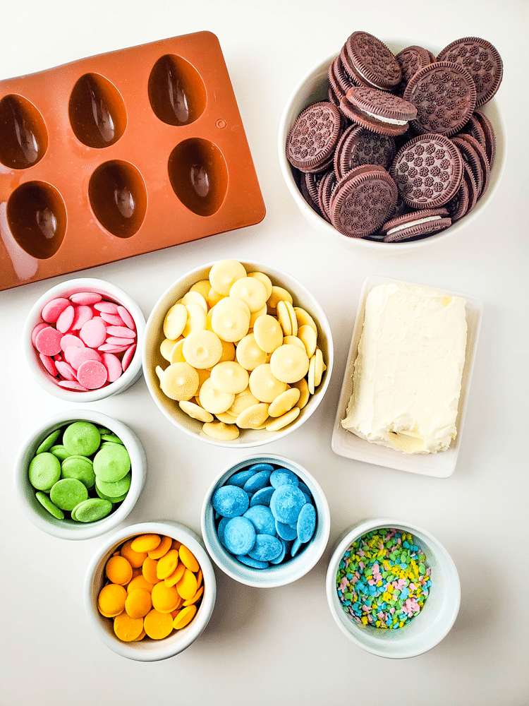 Ingreidents needed - egg mold, bowl of Oreos, white candy melts, pink, green, yellow, and blue candy melts in smaller bowls, sprinkles, and cream cheese.