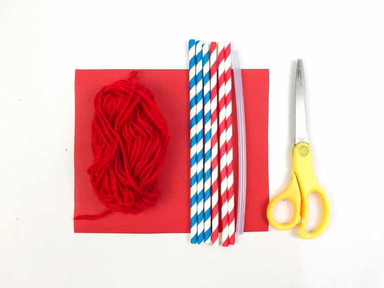 blue and white paper straws, red and white paper straws, red yarn, red paper, and scissors shown.