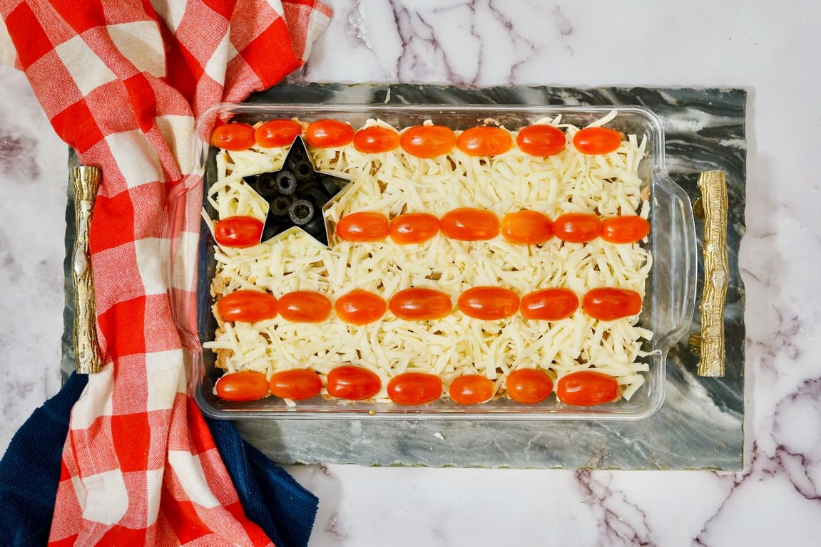 Bean layer dip all done with cherry tomatoes cut in half and placed to look like stripes. 