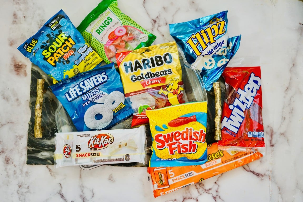 Various candies to make your flag - blue sour patch kids, white mints, white chocolate kit kat, red Swedish fish, red twizzlers, white chocolate covered pretzels, and gummy bears. 
