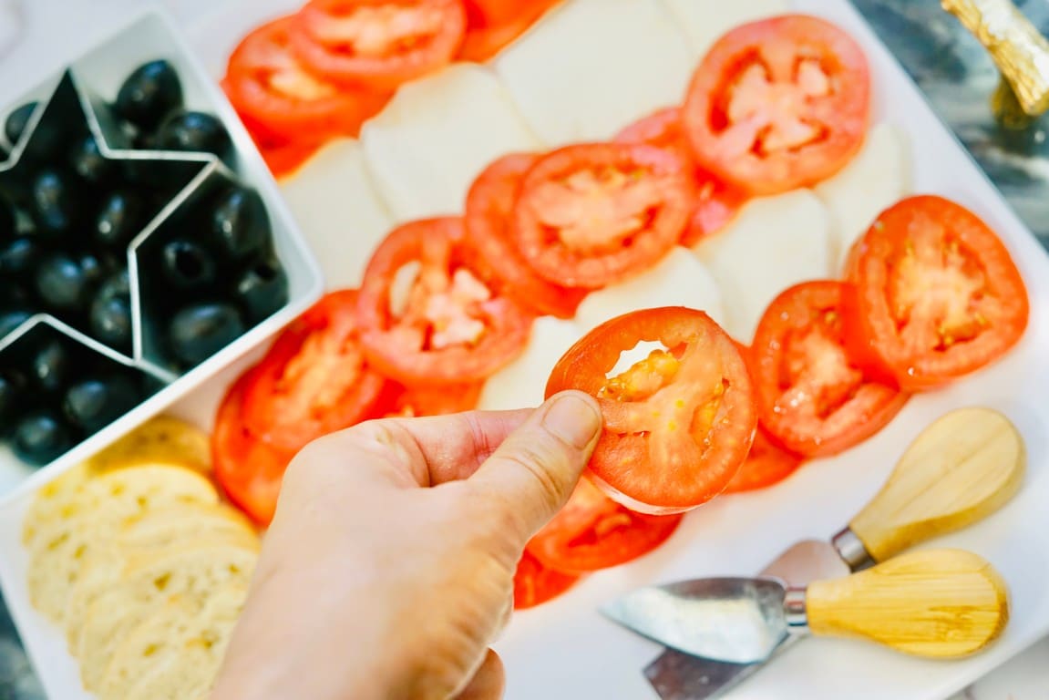 A hand holding a tomato lining them up. 
